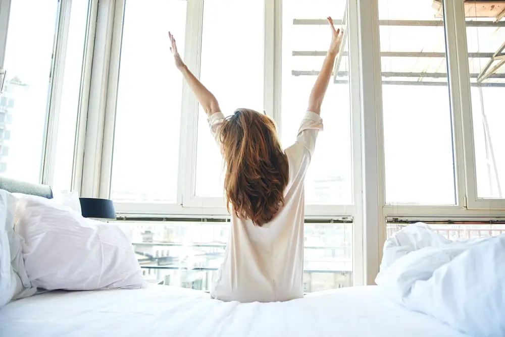 ผู้หญิงกำลังยืดร่างกายหลังตื่นนอน เตรียมพร้อมทำกิจกรรมตอนเช้า